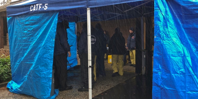 National Urban Search & Rescue Response System Orange County CATF-5 team members take cover from the rain in Paradise, Calif., on Friday. (Associated Press)