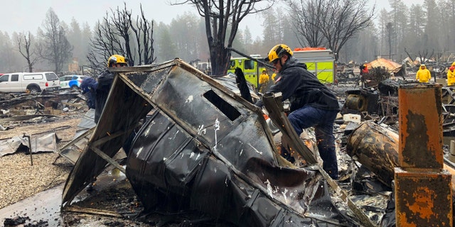 Steven McKnight, right, and Daniel Hansen saw through large pieces of sheet metal so they can be moved to allow cadaver dogs to search beneath them for signs of human remains at a mobile home park in Paradise, Calif., Friday, Nov. 23, 2018. (AP Photo/Kathleen Ronayne)