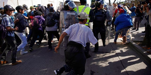 Migrants break past a line of police as they run toward the Chaparral border crossing in Tijuana, Mexico, Sunday, Nov. 25, 2018, near the San Ysidro entry point into the U.S. More than 5,000 migrants are camped in and around a sports complex in Tijuana after making their way through Mexico in recent weeks via caravan. (AP Photo/Ramon Espinosa)