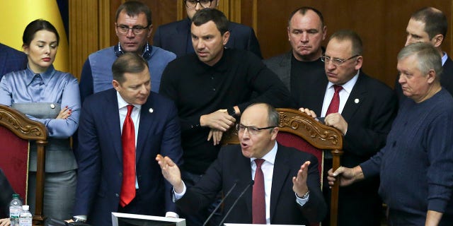 Ukrainian lawmakers listen to parliament speaker Andriy Parubiy, center, during a parliament session in Kiev, Ukraine, Monday, Nov. 26, 2018. Ukrainian President Petro Poroshenko has signed a bill to impose martial law in the country in the wake of Russia's seizure of three ships and their crews. The Supreme Rada is due to vote on the issue later Monday for it to go into force. (AP Photo/Efrem Lukatsky)