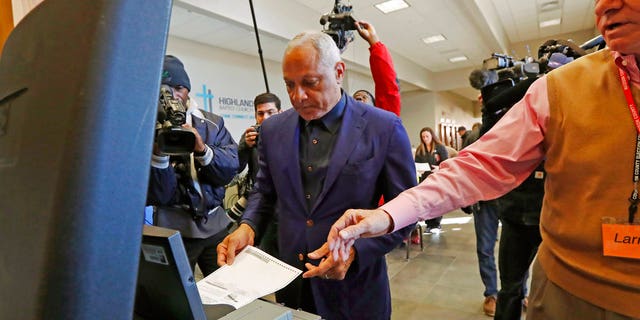 Democrat Mike Espy, left feeds his ballot into the submission machine, as directed by poll manager Larry Greer, Tuesday, Nov. 27, 2018 in Ridgeland, Miss. Mississippi voters are deciding the last U.S. Senate race of the midterms, choosing between Espy and Republican Sen. Cindy Hyde-Smith. (AP Photo/Rogelio V. Solis)