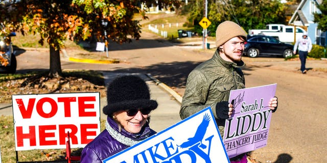 Susan Fino, left, holds a sign for U.S. Senate candidate Mike Espy and Logan Liddy holds one for Susan Liddy, a candidate for judge in the Chancery Court, District 18, Place 1 race at the Oxford Community Center in Oxford, Miss. on Tuesday, November 27, 2018. Mississippians are casting their ballots in runoff elections, including a U.S. Senate race pitting Republican Cindy Hyde-Smith against Democrat Mike Espy. (Bruce Newman/The Oxford Eagle via AP)