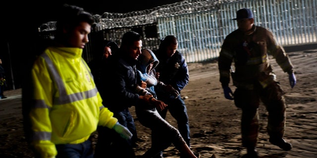 Authorities hold a Honduran migrant who was rescued after he tried to cross the US border by the sea in Tijuana beach, Mexico, Thursday, Nov. 29, 2018. (AP Photo/Ramon Espinosa)