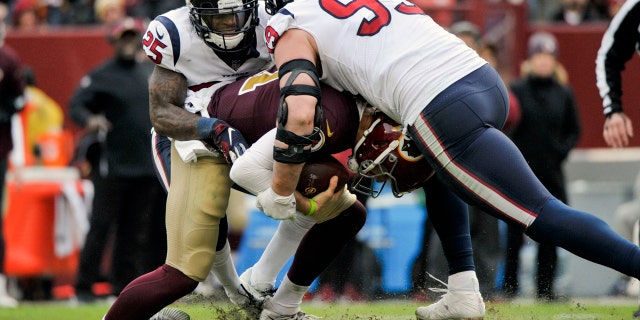 Washington Redskins quarterback Alex Smith (11) ankle is injured as he is sacked by Houston Texans defensive end J.J. Watt (99) and Houston Texans strong safety Kareem Jackson (25) during the second half of an NFL football game, Sunday, Nov. 18, 2018 in Landover, Md. (AP Photo/Mark Tenally)