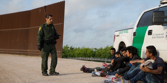 A Border Patrol agent apprehends illegal immigrants shortly after they crossed the border from Mexico into the United States on Monday, March 26, 2018 in the Rio Grande Valley Sector near McAllen, Texas.