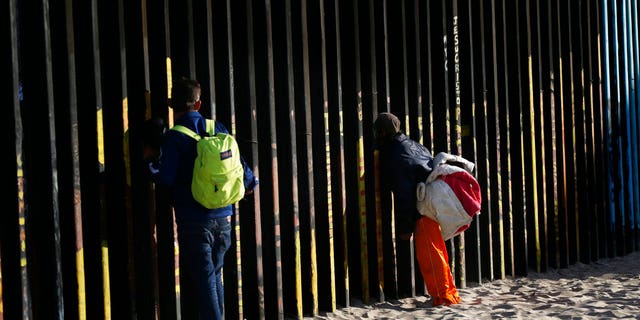 Central American migrants look through the border structure expecting top make an illegal crossing into the U.S., seen from the Mexican side where the border meets the Pacific Ocean, Friday, Nov. 16, 2018. As thousands of migrants of asylum-seekers converge on the doorstep of the United States, what they won't find are armed American soldiers standing guard, that's because U.S. military troops are prohibited from carrying out law enforcement duties. (AP Photo/Marco Ugarte)