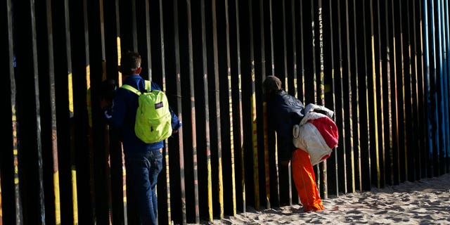 Central American migrants look through the border structure expecting top make an illegal crossing into the U.S., seen from the Mexican side where the border meets the Pacific Ocean, Friday, Nov. 16, 2018. As thousands of migrants of asylum-seekers converge on the doorstep of the United States, what they won't find are armed American soldiers standing guard, that's because U.S. military troops are prohibited from carrying out law enforcement duties. (AP Photo/Marco Ugarte)