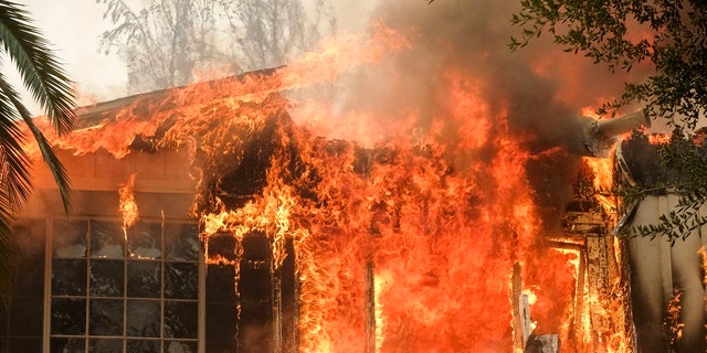 The Woolsey Fire burns a home near Malibu Lake in Malibu, Calif.