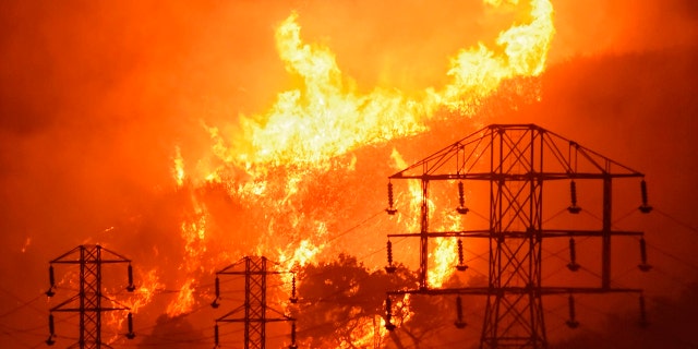 FILE - Flames burn near power lines in Montecito, Calif., Dec. 16, 2017. (Mike Eliason/Santa Barbara County Fire Department via AP)