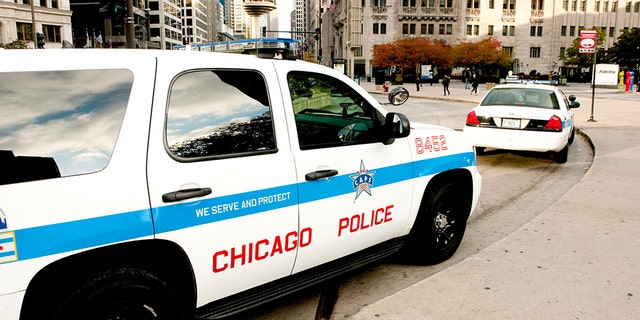  Chicago police cars parked along Michigan avenue in downtown with people passing by early in the morning.