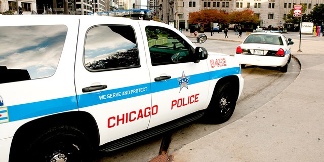  Chicago police cars parked along Michigan avenue in downtown with people passing by early in the morning.