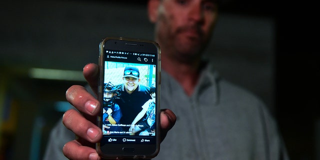 Jason Coffman displays a photo of his son Cody outside the Thousands Oaks Teene Center. He said the 22-year-old lost his life in the tragedy.