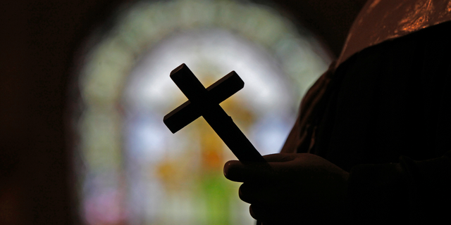 FILE - This Dec. 1, 2012 file photo shows a silhouette of a crucifix and a stained glass window inside a Catholic Church in New Orleans. As U.S. Catholic bishops gather for an important national assembly, the clergy sex abuse crisis dominates their agenda. But it's only one of several daunting challenges facing the nation's largest religious denomination. While federal and state law enforcement agencies widen their investigations of abuse, the church finds itself with ever fewer priests and nuns in service. (AP Photo/Gerald Herbert)