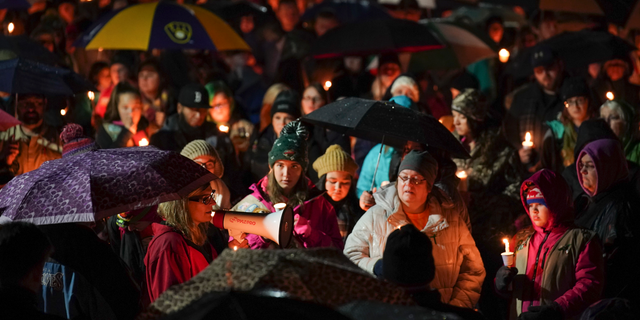 Sherri Jasper, a Girl Scout board member and counselor at Halmstad Elementary School, leads the program for a candlelight vigil at the school in Chippewa Falls, Wis., Sunday evening, Nov. 4, 2018. The western Wisconsin community on Sunday was grieving the deaths of three Girl Scouts and a parent who were collecting trash Saturday along a rural highway when police say a pickup truck veered off the road and hit them before speeding away. The 21-year-old driver, Colten Treu of Chippewa Falls, sped off but later surrendered. He will be charged with four counts of homicide, Lake Hallie police Sgt. Daniel Sokup said. (Jeff Wheeler/Star Tribune via AP)