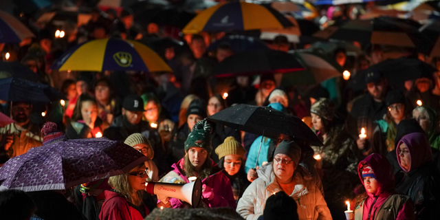 Sherri Jasper, a Girl Scout board member and counselor at Halmstad Elementary School, leads the program for a candlelight vigil at the school in Chippewa Falls, Wis., Sunday evening, Nov. 4, 2018. The western Wisconsin community on Sunday was grieving the deaths of three Girl Scouts and a parent who were collecting trash Saturday along a rural highway when police say a pickup truck veered off the road and hit them before speeding away. The 21-year-old driver, Colten Treu of Chippewa Falls, sped off but later surrendered. He will be charged with four counts of homicide, Lake Hallie police Sgt. Daniel Sokup said. (Jeff Wheeler/Star Tribune via AP)
