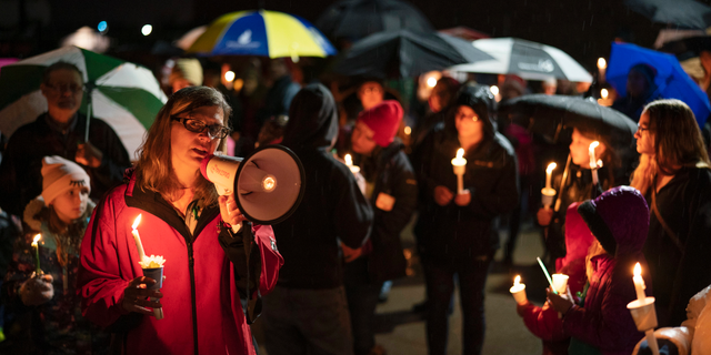 Sherri Jasper, a Girl Scout board member and counselor at Halmstad Elementary School, leads the program for a candlelight vigil at the school in Chippewa Falls, Wis., Sunday evening, Nov. 4, 2018. The western Wisconsin community on Sunday was grieving the deaths of three Girl Scouts and a parent who were collecting trash Saturday along a rural highway when police say a pickup truck veered off the road and hit them before speeding away. The 21-year-old driver, Colten Treu of Chippewa Falls, sped off but later surrendered. He will be charged with four counts of homicide, Lake Hallie police Sgt. Daniel Sokup said. (Jeff Wheeler/Star Tribune via AP)