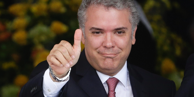 FILE - In this Sept. 10, 2018 file photo, Colombia's President Ivan Duque gives a thumbs up to the press during a welcoming ceremony for him at the presidential palace in Panama City. As Duque completes his first 100 days in office, his administration has been beset by street protests and an unruly congress that has blocked some of his flagship initiatives. (AP Photo/Arnulfo Franco, File)