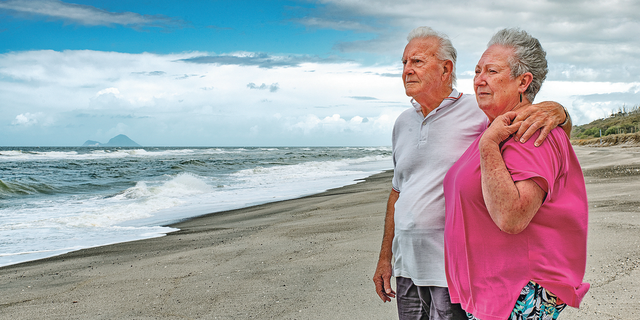 In this Oct. 29, 2018 photo fisherman Gus Hutt is with his wife Sue where he saved saved 18-month-old Malachi Reeve after he had escaped from his parents' tent at Matata Beach, near Whakatane, New Zealand. Hutt was fishing when he plucked a toddler from the ocean in a "miraculous" rescue after thinking he was watching a doll float past. (Troy Baker/Whakatane Beacon via AP)