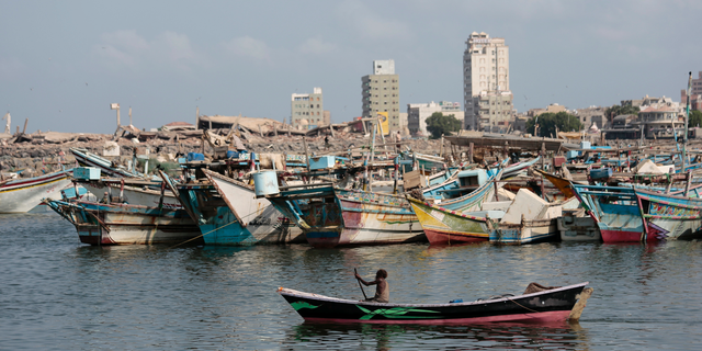 FILE - In this Friday Sept. 28, 2018 file photo, a fisherman paddles his boat past destroyed buildings on the coast of the port city of Hodeida, Yemen. Amnesty International said warned late Wednesday. Nov. 7, 2018 that Yemen's rebels have taken up positions on a hospital rooftop in the contested Red Sea city of Hodeida that a Saudi-led coalition is trying to capture. This raises concerns the Shiite rebels, known as Houthis, plan to use the patients at the Hodeida hospital as human shields to ward off airstrikes from the coalition. Amnesty is urging the warring sides to protect civilians. (AP Photo/Hani Mohammed, File)