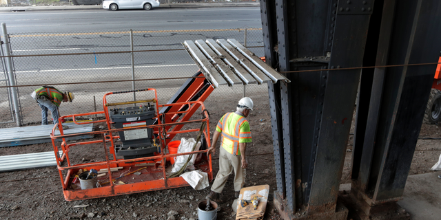 FILE- In this Aug. 15, 2018, file photo workers labor on scaffolding below the Route 495 viaduct ahead of a project to remodel the bridge which feeds into the Lincoln Tunnel in North Bergen, N.J. On Thursday, Nov. 1, the Commerce Department reports on U.S. construction spending in September. (AP Photo/Julio Cortez, File)