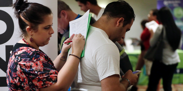 FILE- In this Jan. 30, 2018, file photo, Loredana Gonzalez, of Doral, Fla., fills out a job application at a JobNewsUSA job fair in Miami Lakes, Fla. On Friday, Nov. 2, the U.S. government issues the October jobs report. (AP Photo/Lynne Sladky, File)