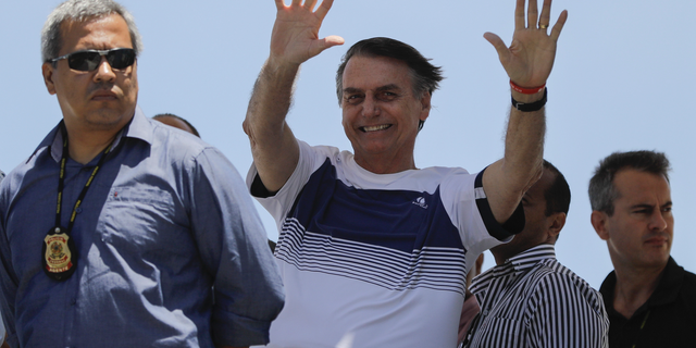 Brazil's President-elect Jair Bolsonaro waves at supporters as he arrives to watch an aerial performance by the private pilots' group “Esquadrilha do Ceu" or “Sky Squadron", at Barra beach in Rio de Janeiro, Brazil, Wednesday, Oct. 31, 2018. Bolsonaro appeared in public Tuesday for the first time as president-elect. He visited a church led by ultraconservative pastor Silas Malafaia and spoke briefly to the faithful on stage. "I am sure that I am not the most capable, but God capacitates the chosen ones," he said. (AP Photo/Leo Correa)