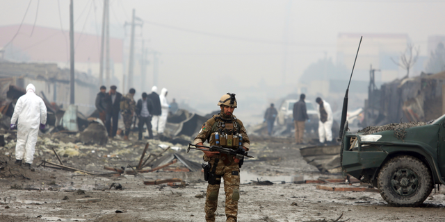 An Afghan security force member walks around the site of suicide bomb attack in Kabul, Afghanistan, Thursday, Nov. 29, 2018. (AP Photo/Rahmat Gul)