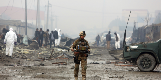 An Afghan security force member walks around the site of suicide bomb attack in Kabul, Afghanistan, Thursday, Nov. 29, 2018. (AP Photo/Rahmat Gul)