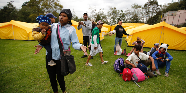 Venezuelan migrants speak to the press as they arrive to a new, refugee-style camp set up by the government in Bogota, Colombia, Tuesday, Nov. 13, 2018. Officials were initially reluctant to open camps for homeless Venezuelan arrivals but now say they have no choice as the number fleeing their nation’s economic and humanitarian crisis continues to rapidly escalate. (AP Photo/Fernando Vergara)