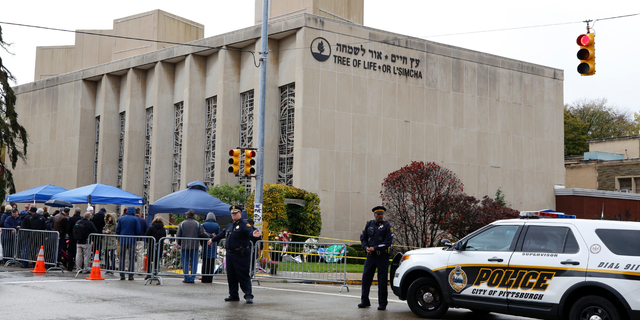 Pittsburgh Police direct traffic as their vehicles close the street adjacent to the Tree of Life Synagogue on Saturday, Nov. 3, 2018, as a curbside Shabbat morning service is held on the street corner in the Squirrel Hill neighborhood of Pittsburgh. The service honored the 11 people killed by a gunman, Oct 27, 2018 while worshipping at the Tree of Life Synagogue. (AP Photo/Gene J. Puskar)