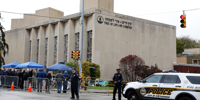 Pittsburgh Police direct traffic as their vehicles close the street adjacent to the Tree of Life Synagogue on Saturday, Nov. 3, 2018, as a curbside Shabbat morning service is held on the street corner in the Squirrel Hill neighborhood of Pittsburgh. The service honored the 11 people killed by a gunman, Oct 27, 2018 while worshipping at the Tree of Life Synagogue. (AP Photo/Gene J. Puskar)