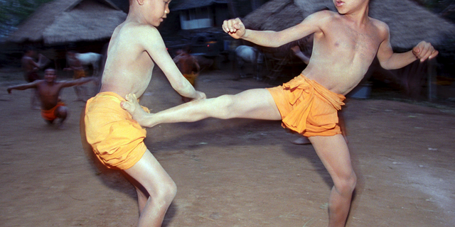 FILE - In this March 19, 2002, file photo, two novice Buddhist monks practice Muay Thai (Thai kickboxing) during a morning training session at the Golden Horse Monastery in northern Thailand. The death of a 13-year-old boy who was knocked out during a Muay Thai boxing match in Thailand has sparked debate over whether to ban child boxing. (AP Photo/David Longstreath, File)