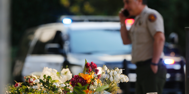 A bouquet of flowers, left by mourners, lays near the site of Wednesday's mass shooting, in Thousand Oaks, Calif., Friday, Nov. 9, 2018. Investigators continue to work to figure out why an ex-Marine opened fire Wednesday evening inside a Southern California country music bar, killing multiple people. (AP Photo/Damian Dovarganes)
