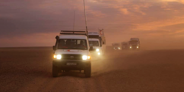 This photo released by the Syrian Arab Red Crescent, shows a convoy of vehicles of the Syrian Arab Red Crescent driving in the Syrian desert heading to Rukban camp between the Jordan and Syria borders, Sunday, Nov. 4, 2018. U.N. officials and volunteers from the Syrian Arab Red Crescent offered vaccinations for children Sunday and distributed much needed aid, the first such assistance since January to reach thousands of people in a remote camp for the displaced on Syria's border with Jordan. Residents say it is the first time they see international humanitarians roaming their desolate camp, where nearly 50,000 have been stranded in a political void. (Syrian Arab Red Crescent via AP)