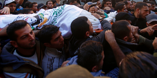 Mourners chant Islamic slogans while carrying the body of Hamas militant commander Nour el-Deen Barakas, who was killed during an Israeli raid late Sunday, during his funeral, at his family house in Khan Younis, southern Gaza Strip, Monday, Nov. 12, 2018. Thousands of mourners in the Gaza Strip buried seven Palestinians, including Barakas, killed after an Israeli incursion into the territory, which also killed one Israeli army officer. The cross-border fighting came just days after Israel and Hamas reached indirect deals, backed by Qatar and Egypt, to allow cash and fuel into Gaza. (AP Photo/Adel Hana)