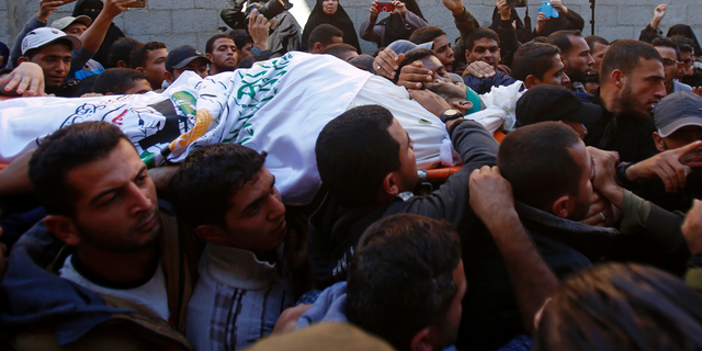 Mourners chant Islamic slogans while carrying the body of Hamas militant commander Nour el-Deen Barakas, who was killed during an Israeli raid late Sunday, during his funeral, at his family house in Khan Younis, southern Gaza Strip, Monday, Nov. 12, 2018. Thousands of mourners in the Gaza Strip buried seven Palestinians, including Barakas, killed after an Israeli incursion into the territory, which also killed one Israeli army officer. The cross-border fighting came just days after Israel and Hamas reached indirect deals, backed by Qatar and Egypt, to allow cash and fuel into Gaza. (AP Photo/Adel Hana)