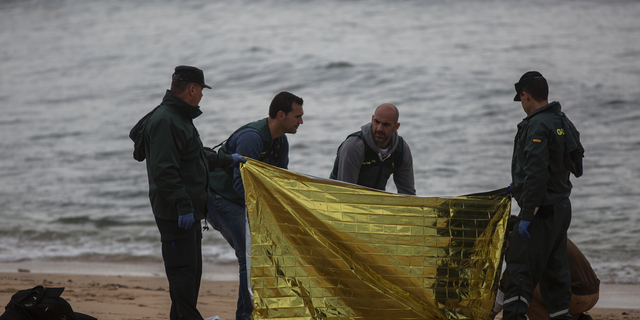 Members of the Spanish Civil Guard inspect the body of a dead migrant found on the beach at the village of Canos de Meca, where seventeen bodies were recovered from the sea after their precarious vessel impacted rocks while trying to reach Spanish coasts in the past week, Barbate, Spain, Monday, Nov. 12, 2018. (AP Photo/Javier Fergo)