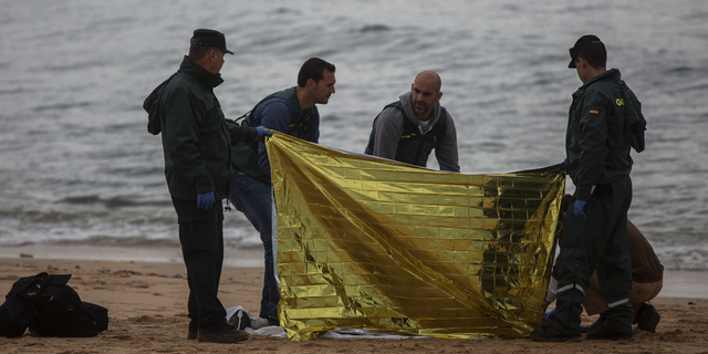 Members of the Spanish Civil Guard inspect the body of a dead migrant found on the beach at the village of Canos de Meca, where seventeen bodies were recovered from the sea after their precarious vessel impacted rocks while trying to reach Spanish coasts in the past week, Barbate, Spain, Monday, Nov. 12, 2018. (AP Photo/Javier Fergo)