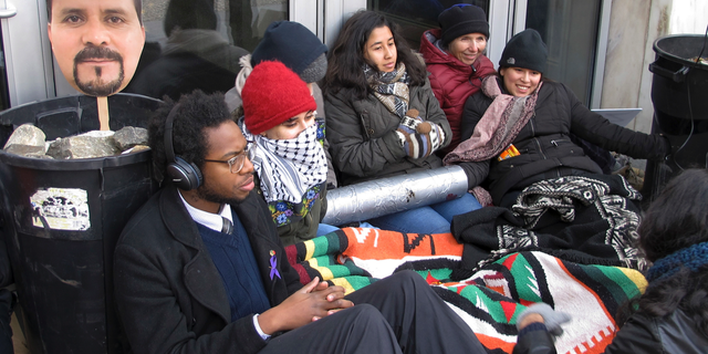 Supporters of Nelson Pinos, an immigrant from Ecuador who has been living in a church for a year to avoid deportation, block the front doors outside the federal building, Friday, Nov. 30, 2018, in Hartford, Conn. Demonstrators are demanding that Immigration and Customs Enforcement officials stay a deportation order and allow Pinos, 44, to go home to his family in time for the holidays. Pinos sought sanctuary in a New Haven church after he was ordered to leave the U.S. a few weeks before Christmas last year. (AP Photo/Dave Collins)