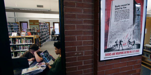 A 1942 Office of War Information poster copy hangs in a hallway of the Rochester Public Library in Rochester, N.H., Thursday, Nov. 8, 2018. A trove of propaganda posters from World War I and II were found recently found after being lost in storage for decades in the library's basement. (AP Photo/Charles Krupa)