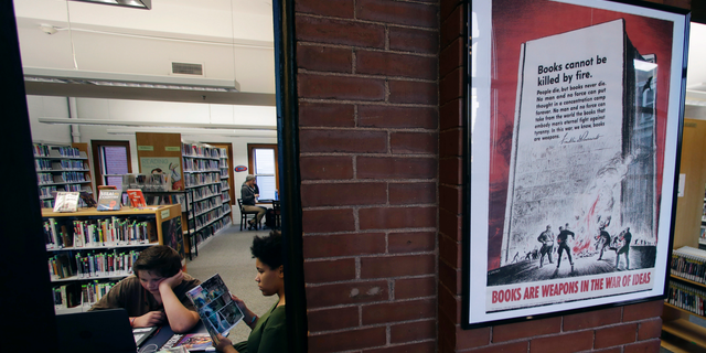 A 1942 Office of War Information poster copy hangs in a hallway of the Rochester Public Library in Rochester, N.H., Thursday, Nov. 8, 2018. A trove of propaganda posters from World War I and II were found recently found after being lost in storage for decades in the library's basement. (AP Photo/Charles Krupa)