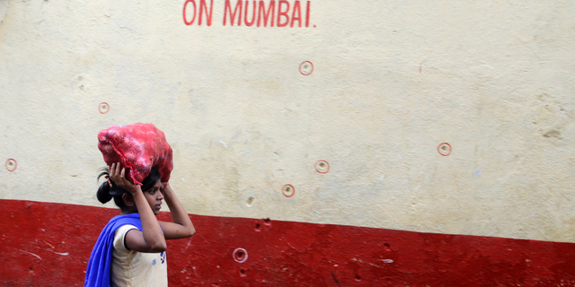 A girl walks past a wall of the Chabad House, with bullet marks on the eve of the tenth anniversary of the Mumbai terror attacks in Mumbai, India.