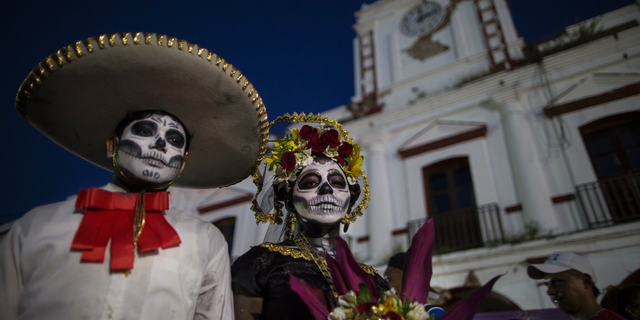 Performers in costume attend a Day of the Dead parade in Juchitan, Mexico, Wednesday, Oct. 31, 2018, the town where a caravan of thousands of Central American migrants are resting for a day as they make their way to the U.S. border. (AP Photo/Rodrigo Abd)