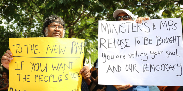 Sri Lankan civil rights activists hold placards during a demonstration outside the official residence of ousted Prime Minister Ranil Wickremesinghe in Colombo, Sri Lanka, Sunday, Nov 4, 2018. Ousted Sri Lankan Prime Minister Ranil Wickremesinghe said Friday there is credible evidence that his replacement is attempting to buy support in Parliament ahead of an expected vote of confidence when it reconvenes. ( AP Photo/Lahiru Harshana)
