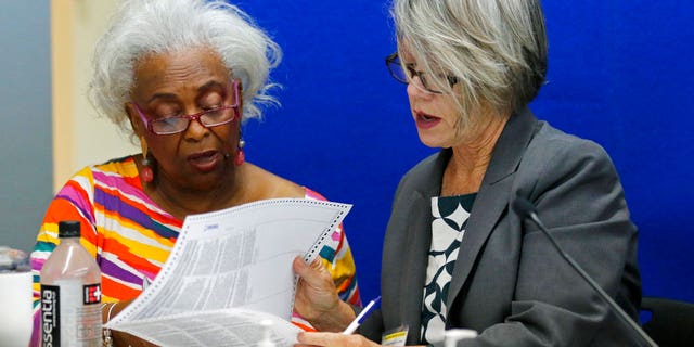 Dr. Brenda Snipes, left, Broward County Supervisor of Elections, looks at a ballot with Betsy Benson, canvasing board chair during a canvasing board meeting on the bitter and tight U.S. Senate race between Republican Gov. Rick Scott and incumbent Democrat Bill Nelson; and in the governor’s race between former Republican U.S. Rep. Ron DeSantis and the Democratic mayor of Tallahassee, Andrew Gillum. (AP Photo/Joe Skipper)