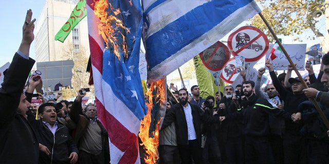 Iranian demonstrators burn representations of the U.S. and Israeli flags during a rally in front of the former U.S. Embassy in Tehran, Iran, on Sunday, Nov. 4, 2018.