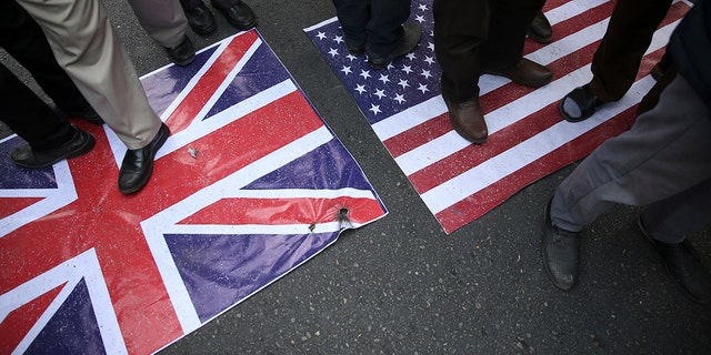 Representations of the U.S. and British flags are walked on by demonstrators during an annual rally in front of the former U.S. Embassy in Tehran, Iran, on Sunday, Nov. 4, 2018.