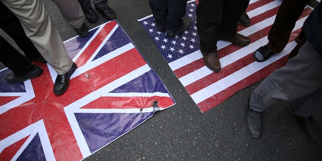 Representations of the U.S. and British flags are walked on by demonstrators during an annual rally in front of the former U.S. Embassy in Tehran, Iran, on Sunday, Nov. 4, 2018.