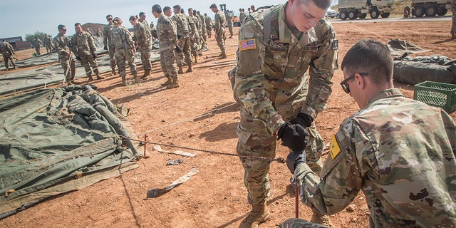 US troops assigned to the 309th Military Intelligence Battalion and the 305th Military Intelligence Battalion are working together to drive a stake into the ground when tents are set up at Fort Huachuca, Arizona on Thursday.