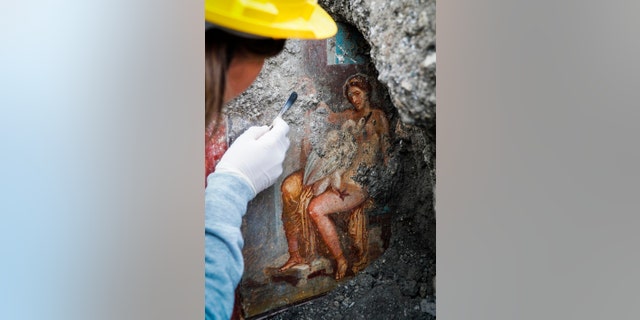 An archeologist cleans up the fresco ''Leda e il cigno'' (Leda and the swan). (Cesare Abbate/ANSA via AP) 